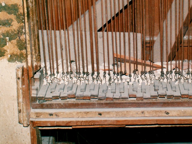 Tastiera con tiranteria in legno allo smontaggio; ricoperta di polvere e calcinacci.
